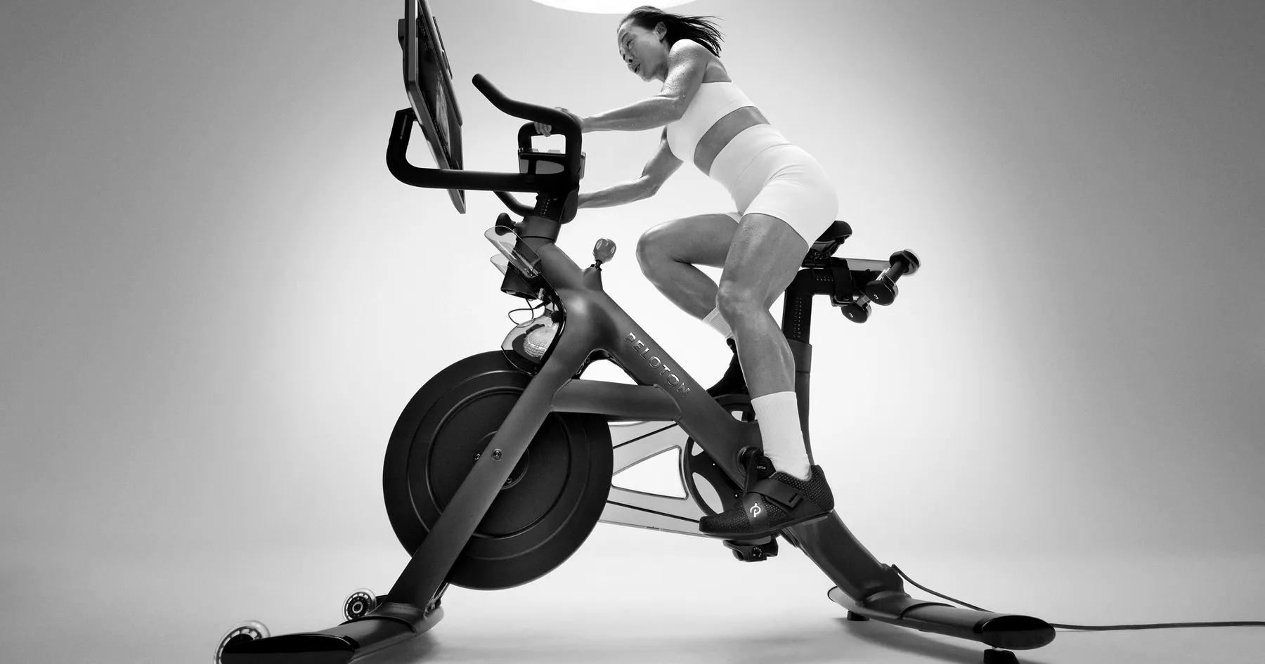 Rider training on a Peloton Bike+ with the class screen in front of them
