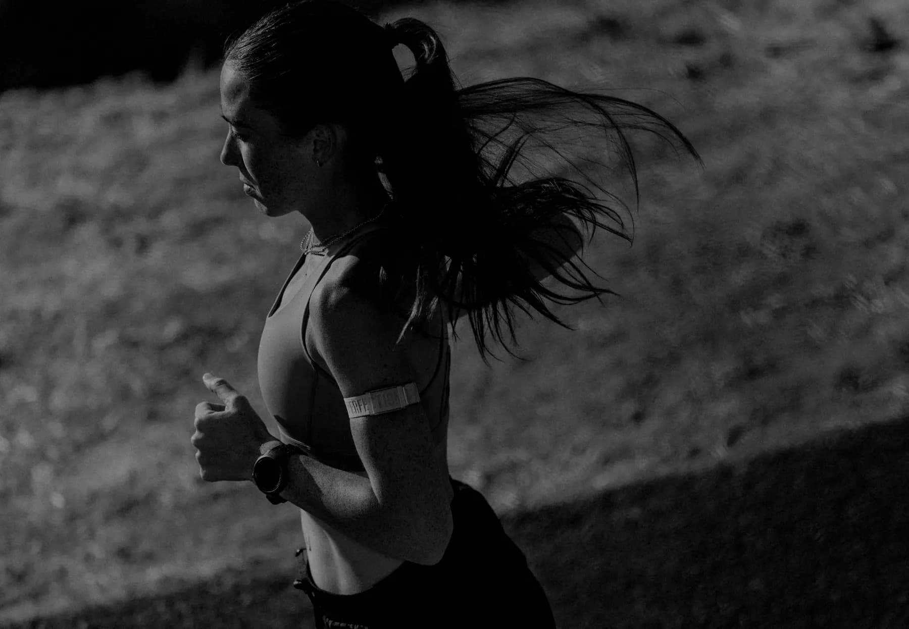 Runner on a hillside wearing a COROS watch and heart-rate armband