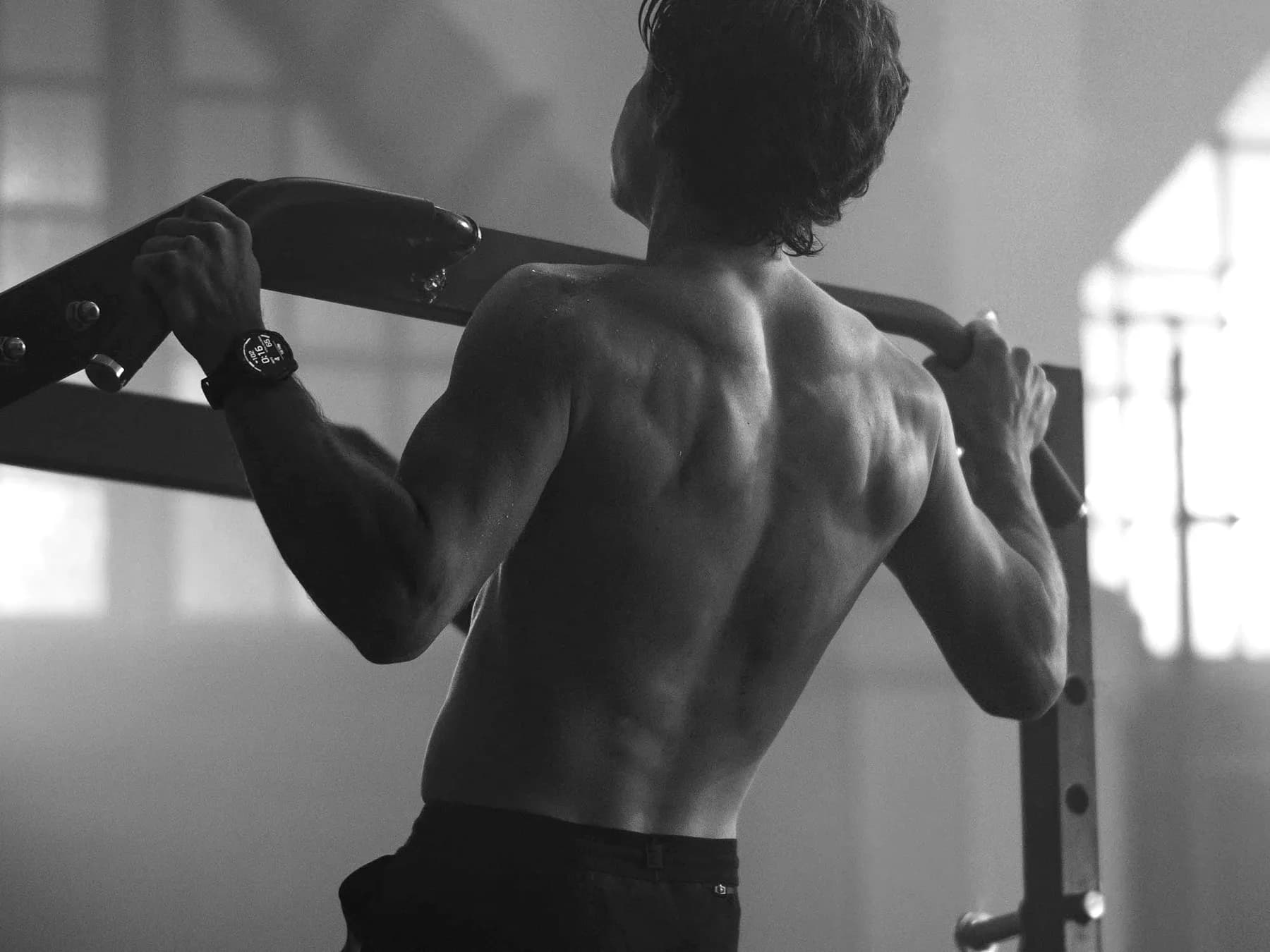 Athlete doing pull-ups wearing a Garmin fēnix watch with the display visible on the wrist