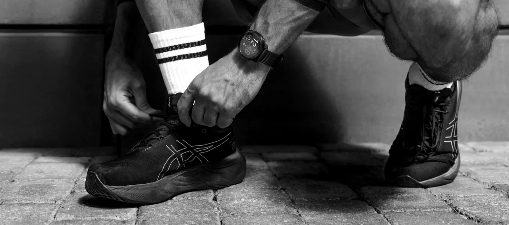 Athlete lacing running shoes wearing a Polar watch on the wrist