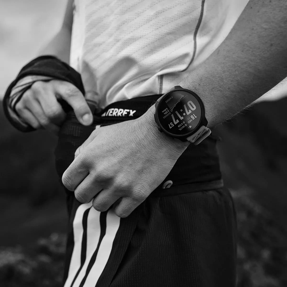 Trail runner adjusting a race belt wearing a Suunto Race watch